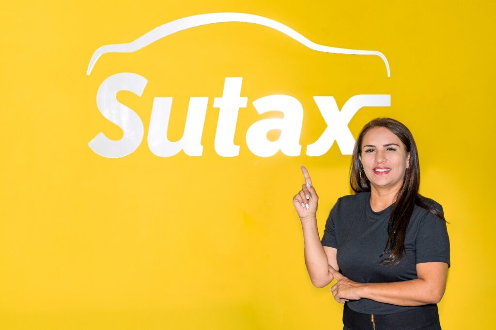 Mujer señalando logo de sutax lugar donde pueden sacar un taxi a crédito